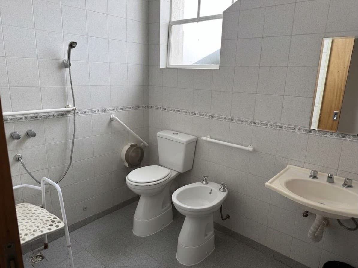 Baño adaptado con barrales y silla de ducha